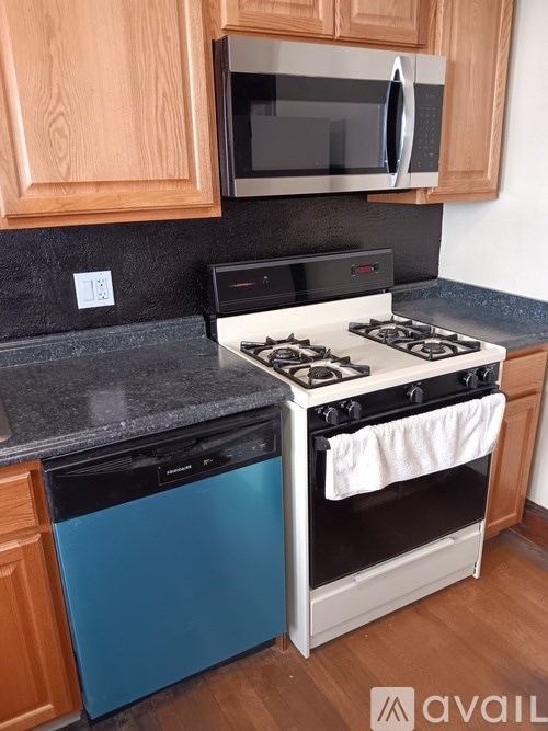 A kitchen with a blue dishwasher and a white stove top oven.