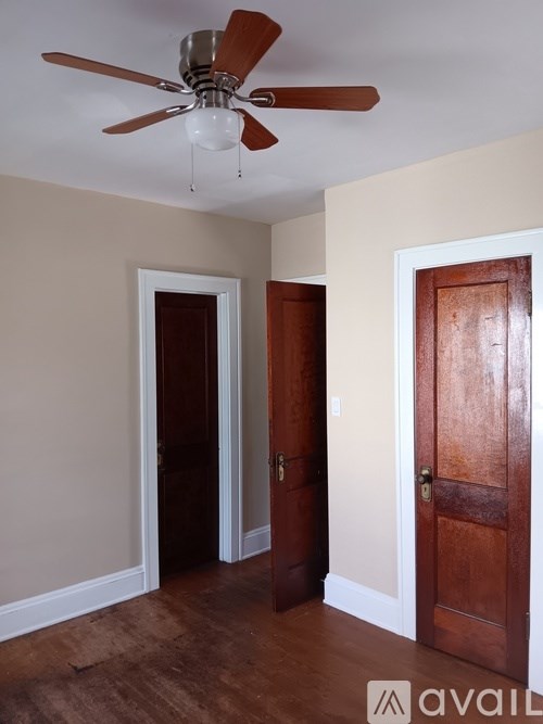 A room with a ceiling fan and two doors.