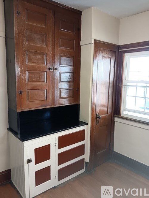 A brown wooden cabinet with a black countertop and white drawers.