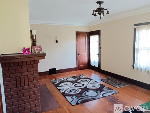 A living room with a brick fireplace and a rug on the floor.
