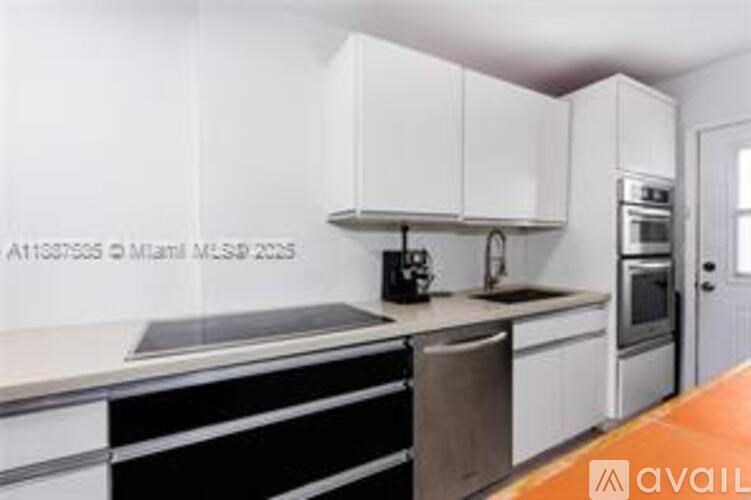 A kitchen with white cabinets and a black counter.