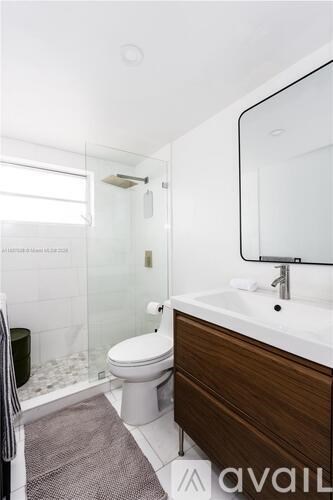 A bathroom with a toilet, sink, and mirror.