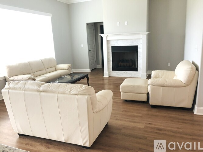 A living room with a white couch, chair, and ottoman.