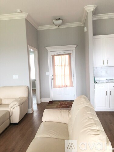 A living room with a white couch and a window with curtains.