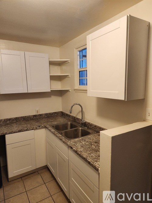 A kitchen with white cabinets and a granite countertop.