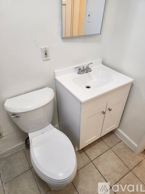 A white toilet sits next to a white sink in a bathroom.