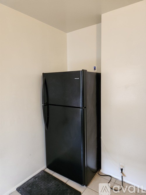 A black fridge in a room with white walls.