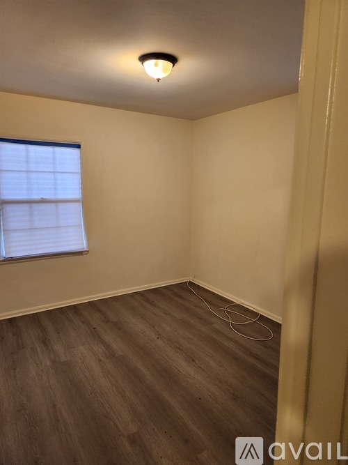 A room with wooden flooring and a window with blinds.