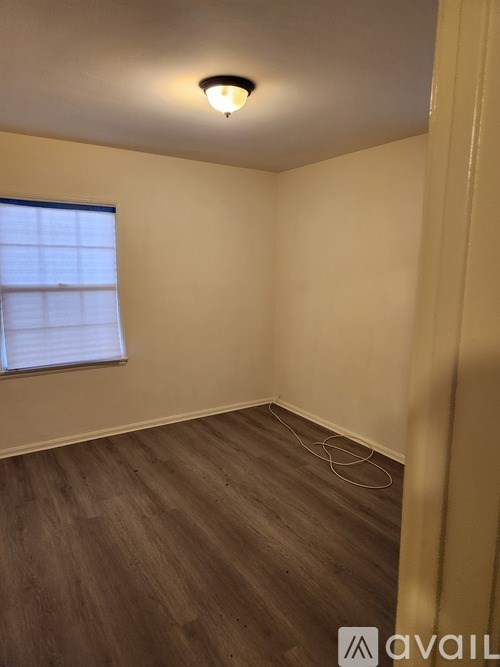 A room with wooden flooring and a window with blinds.