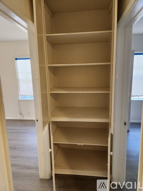 A tall, empty shelving unit with five shelves is in a room with white walls and a window.