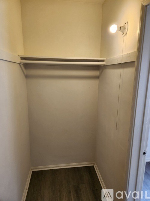 A small, empty room with a light on the wall and a wooden floor.