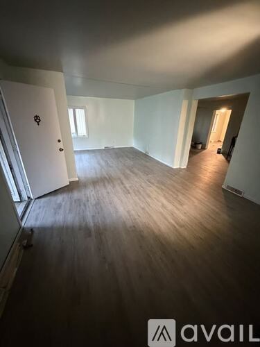 A spacious room with wooden flooring and white walls.
