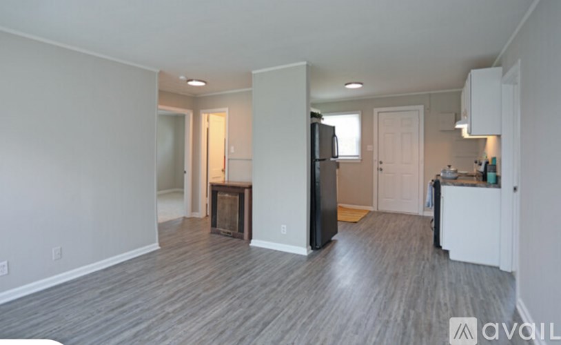 A spacious living room with a fireplace and a kitchen area in the background.