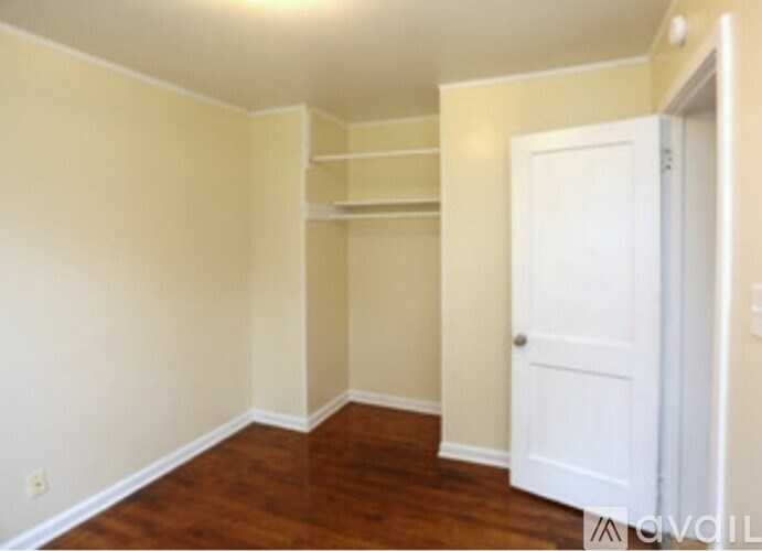 A room with a white door and a wooden floor.