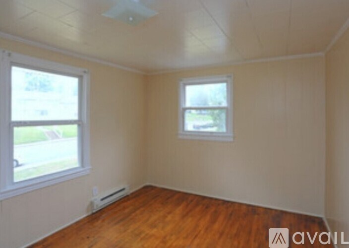 A room with wooden floors and two windows.