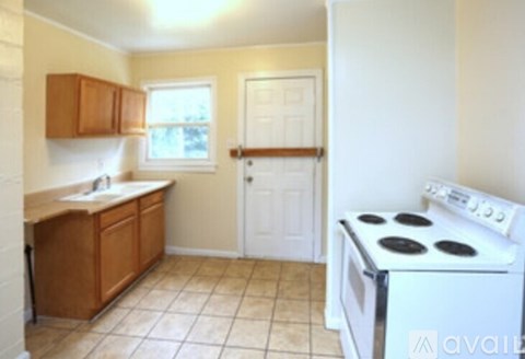 A kitchen with a white stove and wooden cabinets.