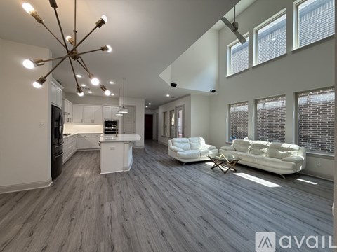 A spacious living room with a kitchen in the background and a white couch in the foreground.