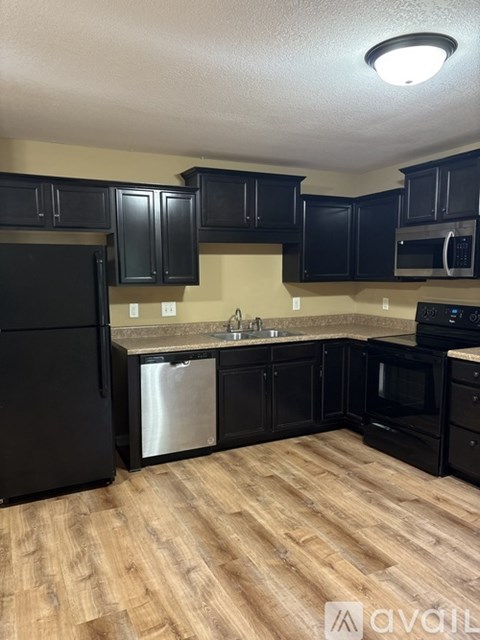 A kitchen with black cabinets and a wooden floor.