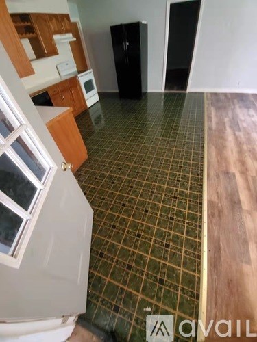 A kitchen with a black fridge and wooden floors.