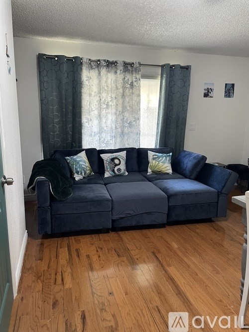 A living room with a blue couch and a window with curtains.