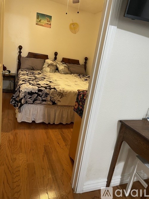 A bedroom with a bed, wooden floor, and a painting on the wall.