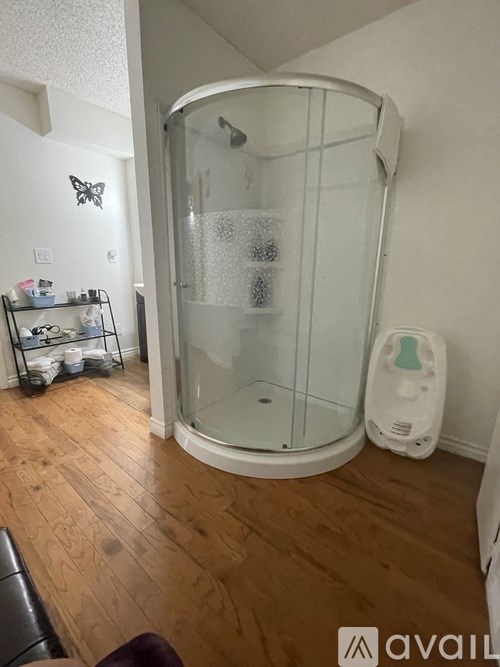 A bathroom with a glass shower stall and a wooden floor.