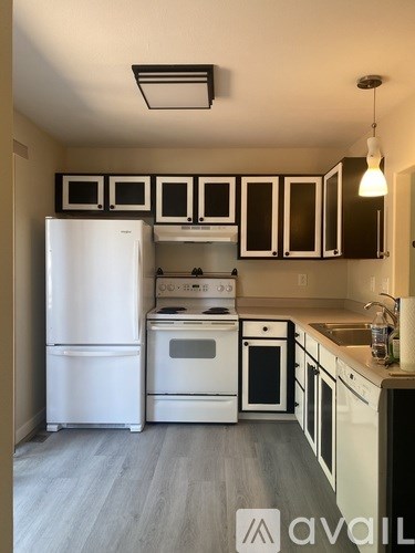 A kitchen with white appliances and black cabinets.