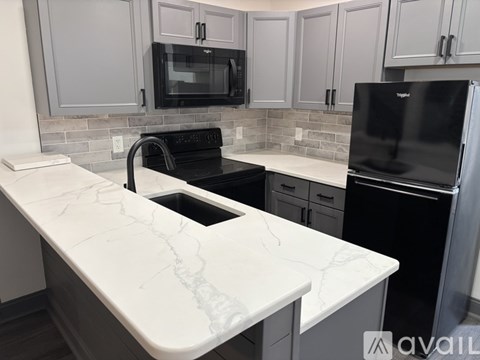 A kitchen with a marble countertop and black appliances.