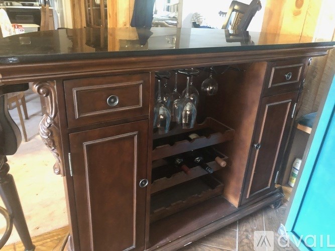 A wooden cabinet with a glass door is filled with wine bottles.