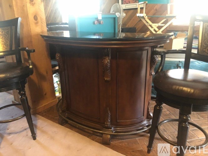 A wooden cabinet with a blue box on top and two chairs with black leather seats.