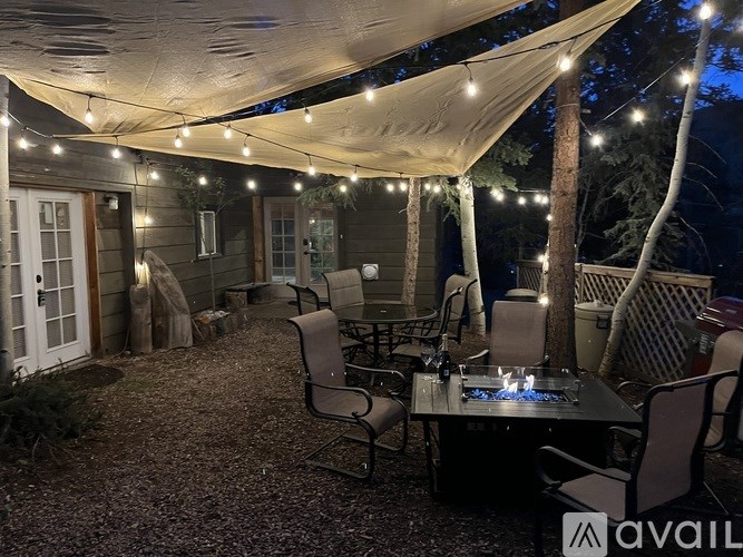A patio area with a table, chairs, and string lights.