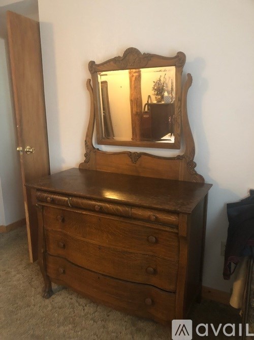 A wooden vanity with a mirror and drawers.