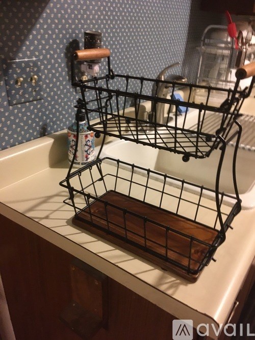 A black wire basket sits on a white sink.