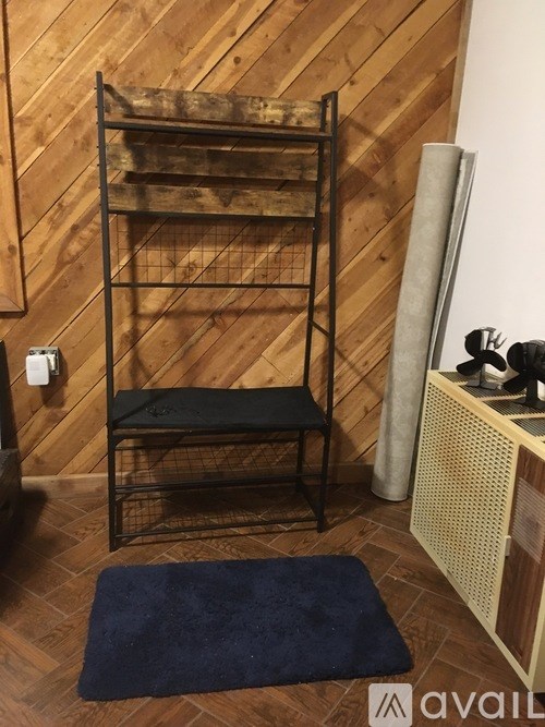 A black metal shelf with a black cushion on top is in a room with wooden walls.