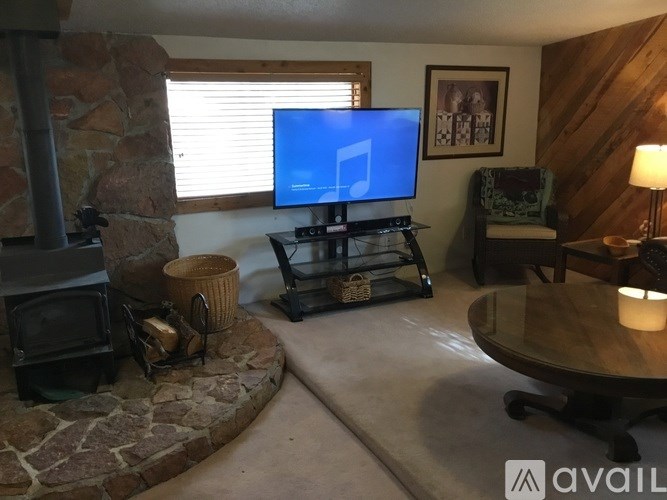 A living room with a stone fireplace and a flat screen TV.