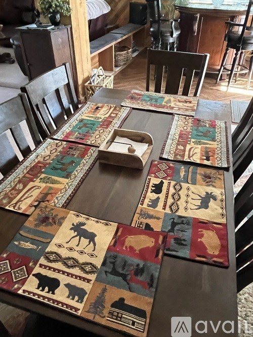 A table with a quilt on it and chairs around it.