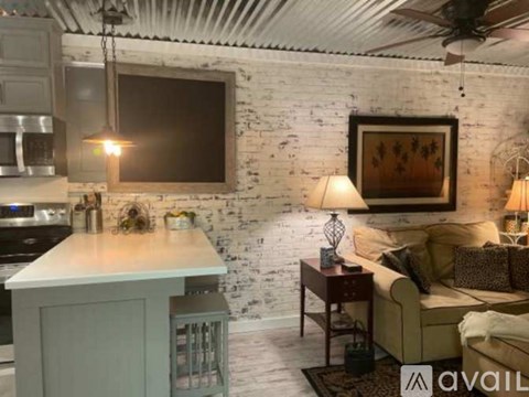 A living room with a couch, a table, and a television mounted on a white brick wall.