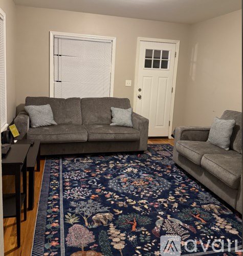A living room with a grey couch and a floral rug.