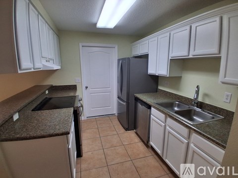 A kitchen with white cabinets and a black refrigerator.