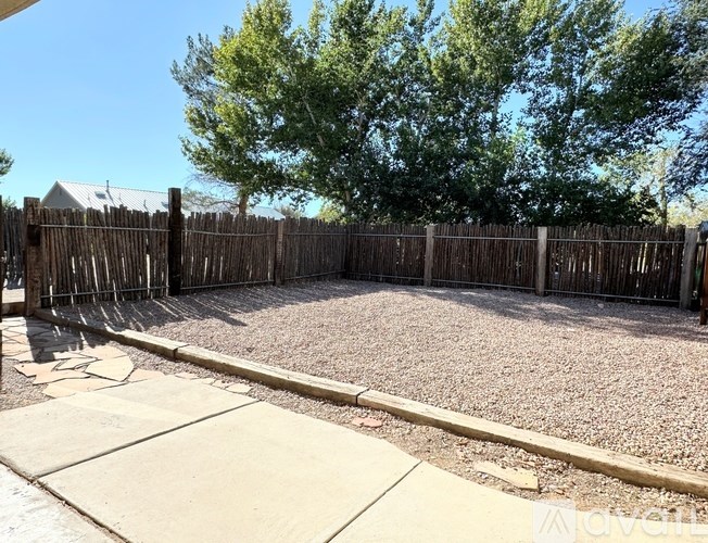 A backyard with a wooden fence and a gravel ground.