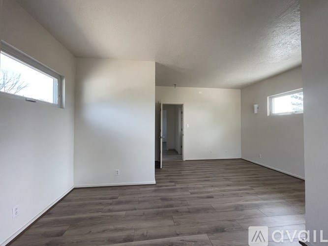 Empty room with wooden flooring and white walls.