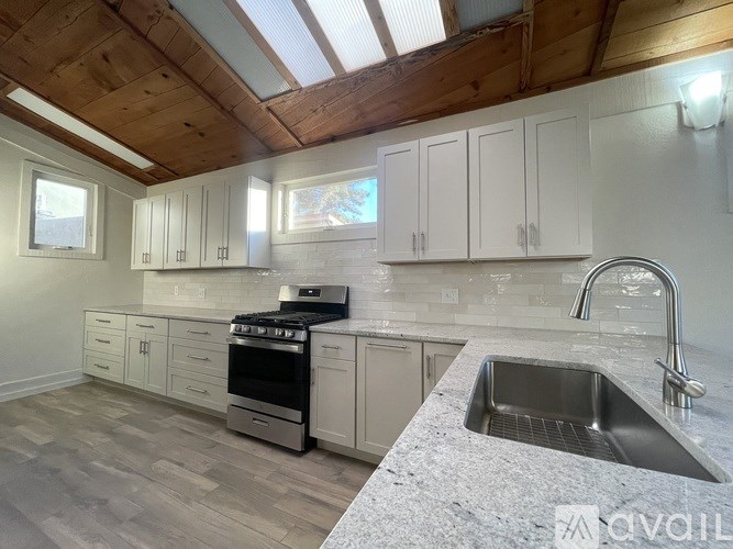 A kitchen with a sink, stove, and cabinets.