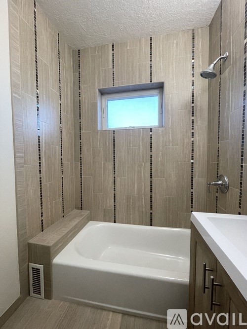 A bathroom with a white tub and a window.