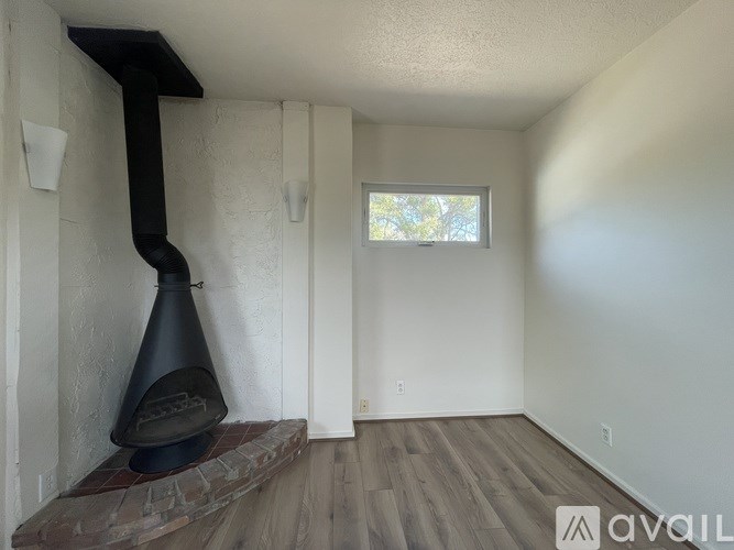 A wood burning stove in a room with a window.