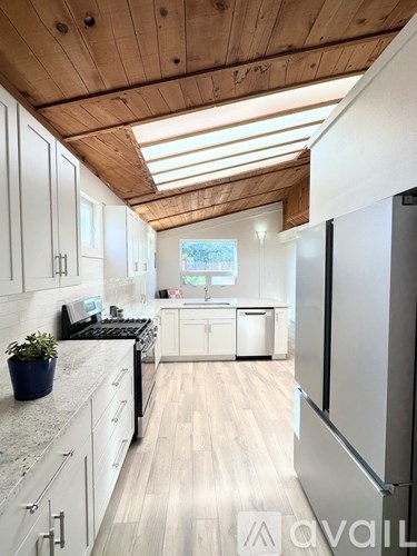A kitchen with wooden ceiling and white cabinets.