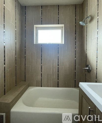 A bathroom with a tub, window, and tiled walls.