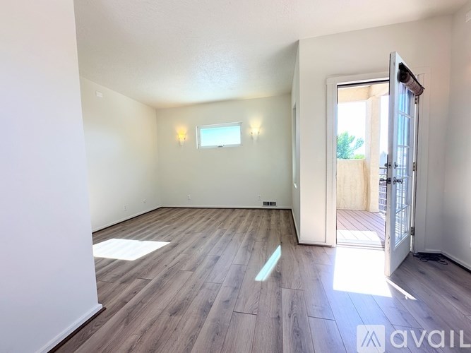 A room with wooden flooring and a door leading to a balcony.