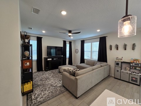 A living room with a grey couch and a ceiling fan.