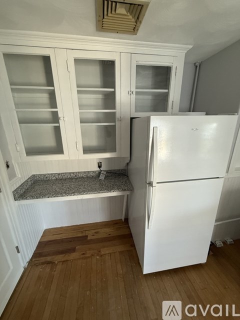 A kitchen with a white fridge and white cabinets with glass doors.