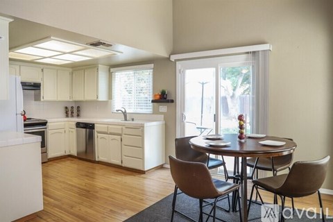 A kitchen with a table and chairs in front of a window.